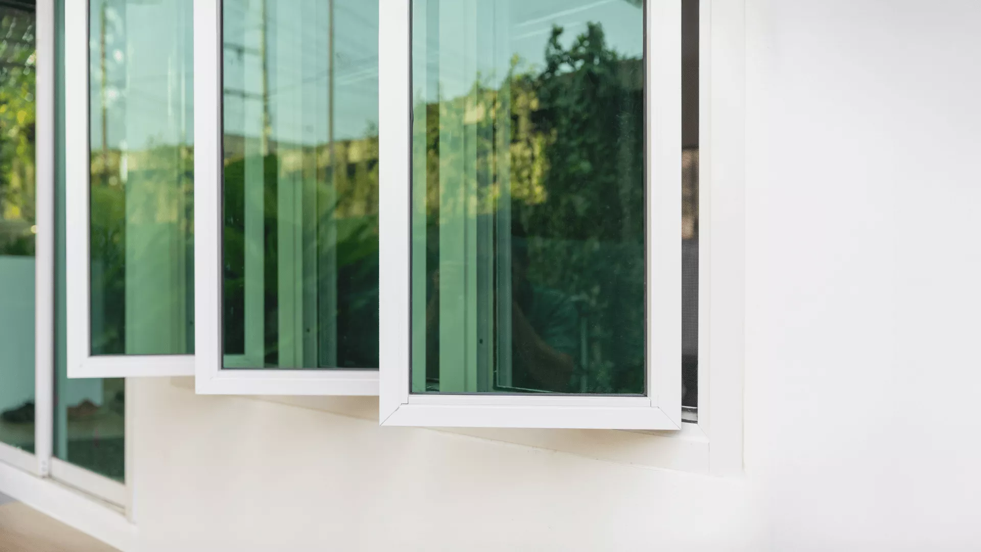 Penahan jendela *casement* aluminium tiga panel pada dinding putih.