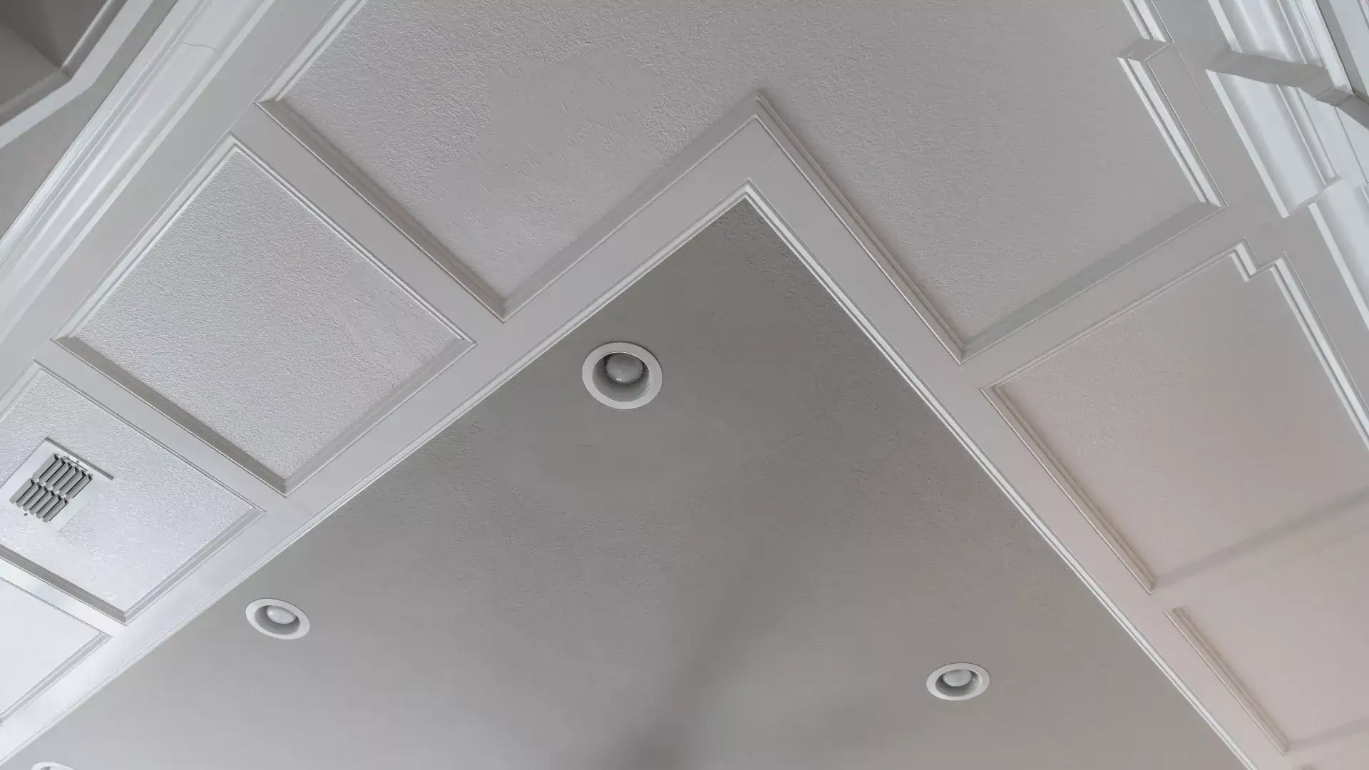 Langit-langit model *tray* dengan aksen kayu putih yang mendetail dan kipas angin gantung, di sebuah rumah baru dengan nuansa warna *beige*-abu-abu (*greige*).